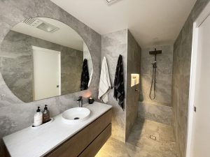 Brand new modern ensuite bathroom with wet room shower and large oval mirror above the sink.