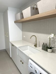 Laundry room renovation in Sydney with washing machine built in, large deep sink, and above sink storage shelf. 