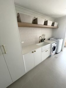 Brand new laundry room renovation in Sydney with washing machine built in, large deep sink, and plenty of storage space.
