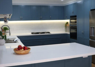 Portrait image of new, blue, modern family kitchen renovation with breakfast bar.